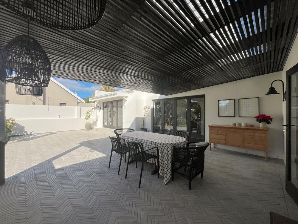 Covered patio dining area with pendant lighting and a slatted timber ceiling