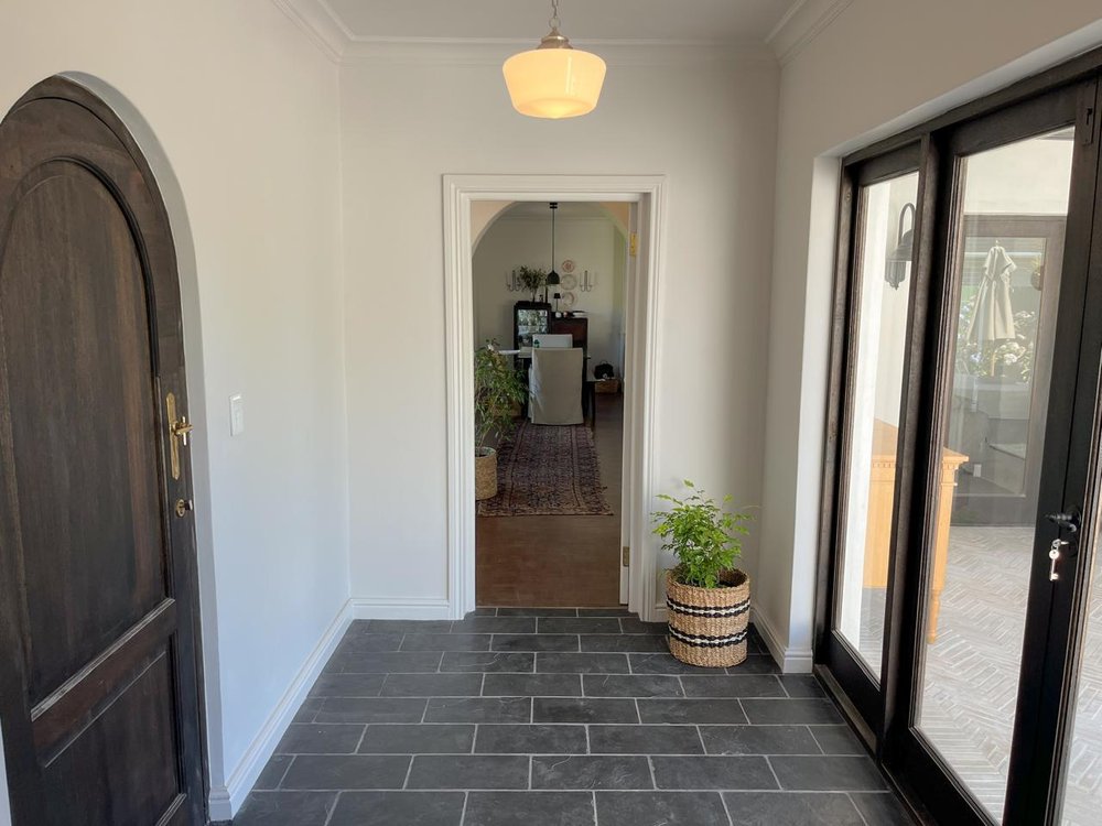 Entrance hallway with dark tile flooring and an arched timber door