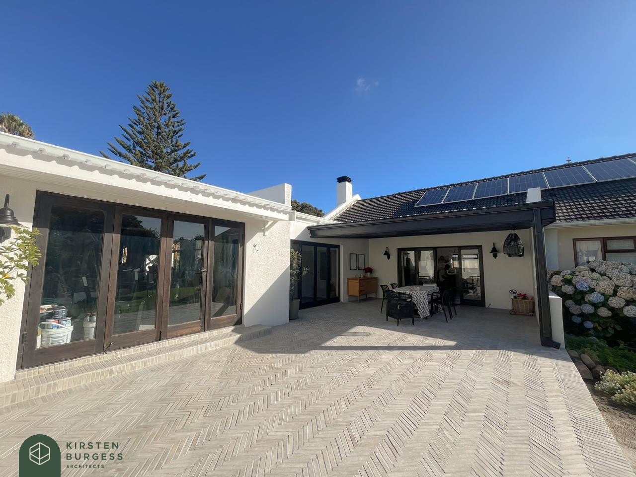 Renovated Meadowridge home with a covered patio, solar panels and a herringbone-paved courtyard
