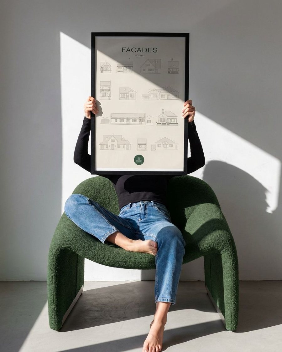 Kirsten Burgess holding a large framed print titled Facades Volume I, showing line drawings of twelve heritage house elevations